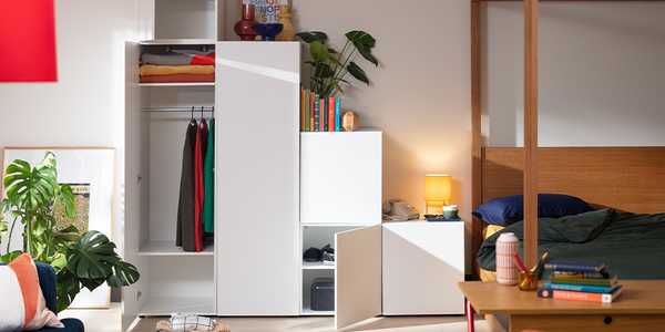 White modular wardrobe in bedroom with compartments for folded and hanging garments.